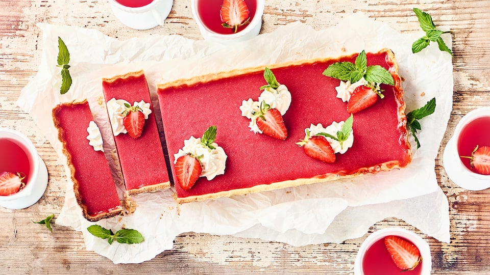 Fruchtig und frisch – genießen Sie unsere Erdbeertarte mit feinem Mürbeteigboden und einer cremiger Erdbeer-Quark-Füllung. Dekorieren Sie die Tarte mit Minze!