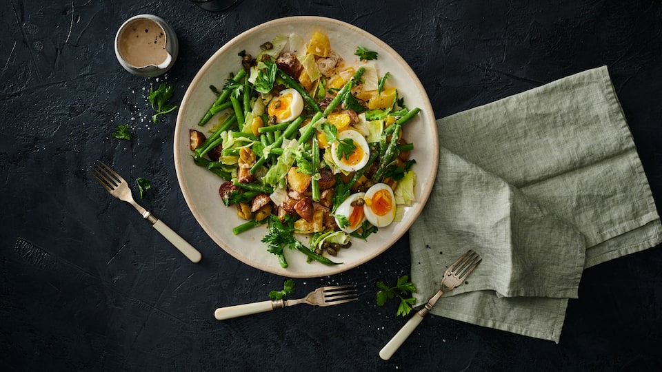 Kartoffelsalat mit grünen Bohnen Kartoffelsalat geht immer! Wir servieren den Klassiker mit grünen Bohnen, Oliven, Thunfisch und gekochten Eiern.
