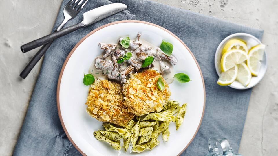 Ein echter Hingucker! Unser Rezept für Veganes Knusperschnitzel aus Seitan - kombiniert mit einer Pilzcreme aus Weißwein und Pesto-Pasta.